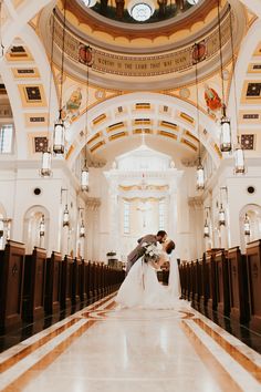 a bride and groom standing in the aisle of a church