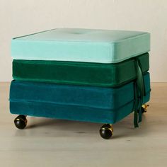 a green ottoman sitting on top of a wooden floor