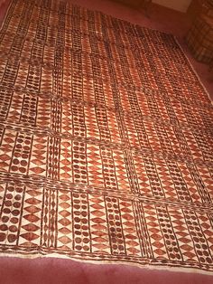 a brown and white blanket sitting on top of a red floor next to a window