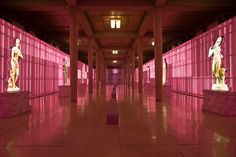 an empty room with pink lighting and statues