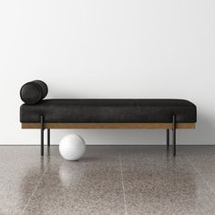 a white ball sitting on top of a wooden bench next to a black leather bench