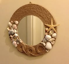 a rope wreath with seashells and starfish hangs on the wall next to a mirror