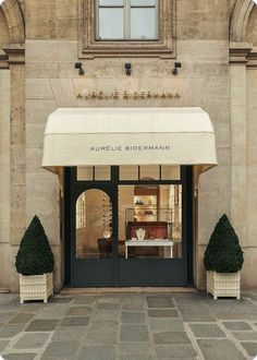 the front entrance to an upscale store with white awnings