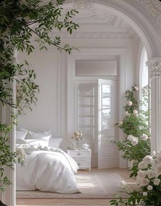 a bedroom with white furniture and flowers on the bed, along with greenery in the corner