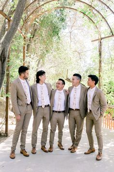 a group of men standing next to each other in front of a wooden arbor structure