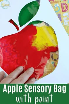 an apple painting with the words apple sensory bag with paint on it and someone's hand