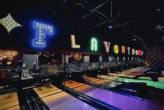 a bowling alley with neon signs and lights on the walls, along with several bowling lanes