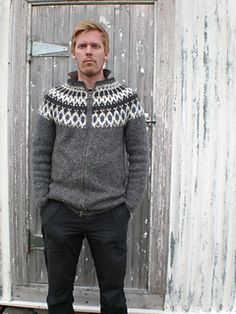 a man standing in front of a door wearing a sweater