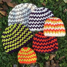 four knitted hats laying on top of green grass