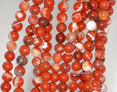 red agate beads with white and brown speckles are arranged on a white surface