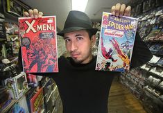 a man holding up two comics in front of his face