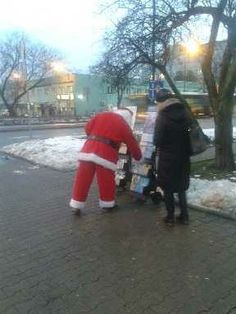 two people dressed as santa claus on the street