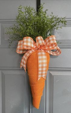 an orange carrot hanging on the side of a gray door with a gingham bow