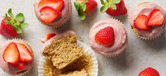 cupcakes with pink frosting and strawberries on the side next to them