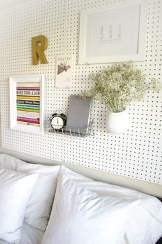 a bed with white sheets and pillows next to a wall with pictures on the wall