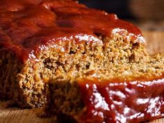 a loaf of meatloaf with ketchup on it sitting on a cutting board