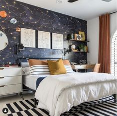 a bedroom decorated in black and white with space themed wallpaper, striped rugs and gold accents