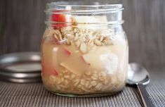 a jar filled with oatmeal sitting on top of a table next to a spoon