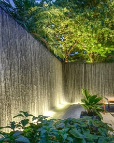 an outdoor area with plants and lights on the wall, along with a bench in the foreground