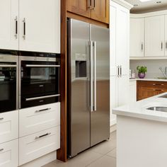 a modern kitchen with stainless steel appliances and white cabinetry, along with wooden cabinets