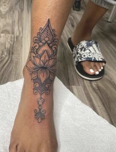 a woman's foot with a tattoo design on the left side of her leg