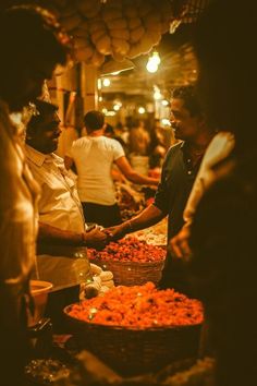 people are shopping at an outdoor market with baskets full of food on the tables and in front of them