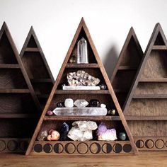 three wooden shelves with different types of rocks and stones in them on a wood floor