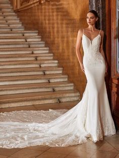 a woman standing in front of a staircase wearing a wedding dress with an open back