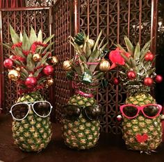 three pineapples with sunglasses are sitting on a table