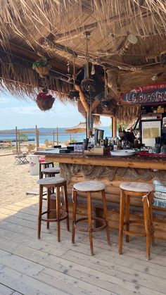 an outdoor bar with stools on the beach