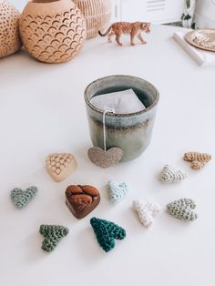 small crocheted hearts are on the table next to a cup