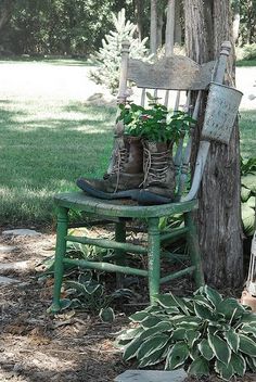 an old wooden chair sitting next to a tree with plants growing in the boots on it