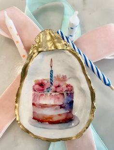 a birthday cake with pink flowers on it and a candle in the center is surrounded by ribbons