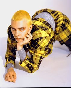 a man in yellow and black checkered pajamas laying on the ground with his hand under his chin