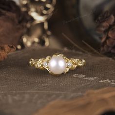 a pearl ring sitting on top of a table next to wine glasses and pine cones