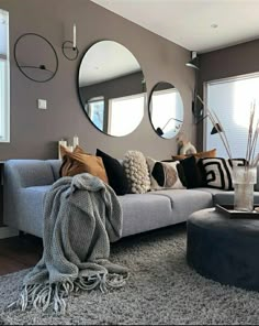 a living room filled with lots of furniture and mirrors on the wall above it's windows