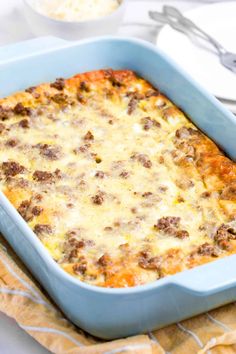 a casserole dish with meat and cheese in it sitting on a napkin next to utensils