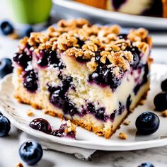 a slice of blueberry cheesecake on a white plate with fresh blueberries around it