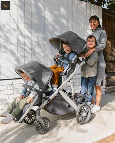 three children standing next to each other in a stroller