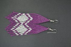 These purple and white beaded earrings feature a diamond in the center of the fringe and a second line that follows the outside of the diamond on the top and bottom.  **Beadwork length is about 3.5 inches. **Width is about 0.75 inch.   **Total length is about 4 inches including the ear wire **Ear wire is sterling silver plated.  **Made in my smoke free home.   **Crafting time for this pair of earrings was about 1.5 hours. Follow me on Facebook for updates on new listings, sneak peeks of projects in process, sales, coupon codes, and more. www.facebook.com/Craftyetsylady/ Traditional Purple Beaded Earrings, White Beaded Earrings, Bead Loom Designs, Second Line, Purple And White, Loom Beading, Beaded Jewelry Diy, 5 Hours, Ear Wire