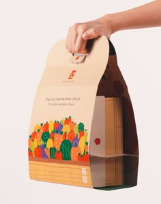 a person holding up a paper bag with an image of vegetables on the front and side