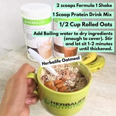 a hand holding a green cup filled with granola and almonds next to two bottles of nutritious drink mix