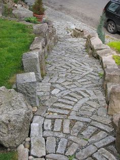 a car is parked on the street next to some rocks and stones that have been laid out