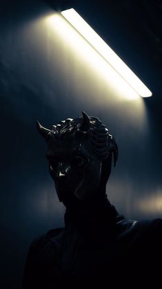 a statue in the dark with a light shining on it's face and head