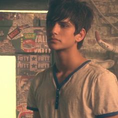 a young man standing in front of a wall with stickers on it's walls