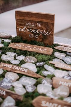 a wooden sign that says and so the adventure begins sitting on top of some rocks