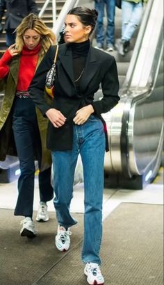 two women are walking down an escalator