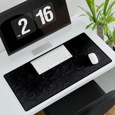 a computer desk with a clock and keyboard on it, next to a potted plant