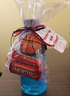 a plastic bag filled with candy and basketballs on top of a wooden table next to a bottle of water