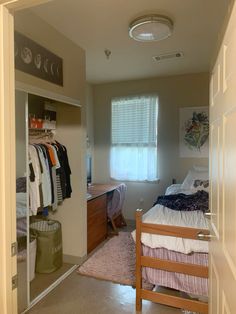 an open door leading to a bedroom with clothes hanging on the rack and closet doors